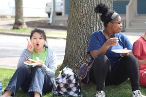 photo courtesy Nicole Pressley and DBCC Photo of girls under tree eating pizza and flashing peace sign.